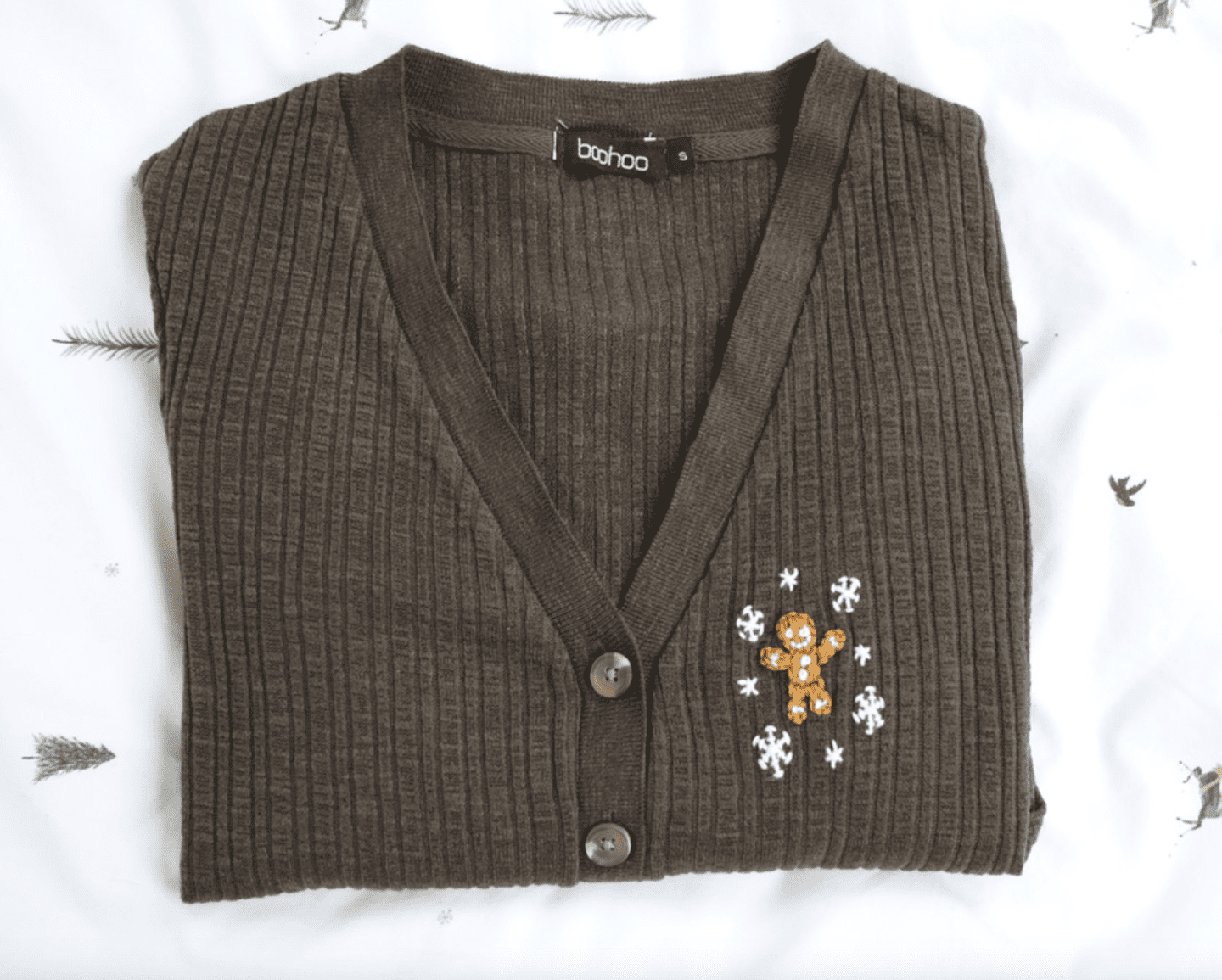 A khaki cardigan hand embroidered with a gingerbread man and snowflakes