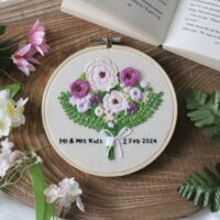 A 6 inch hoop hand embroidered with a purple bouquet of flowers and text reading "Mr & Mrs Katz. 2 Feb 2024"