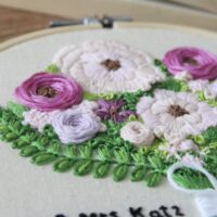 Close up of hand embroidered purple roses and peonies