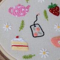 A hand embroidered cake slice, teapot, and teabag