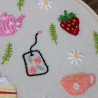 Hand embroidered teapot, teabag, teacup, cake, strawberry, daisies, and leaves