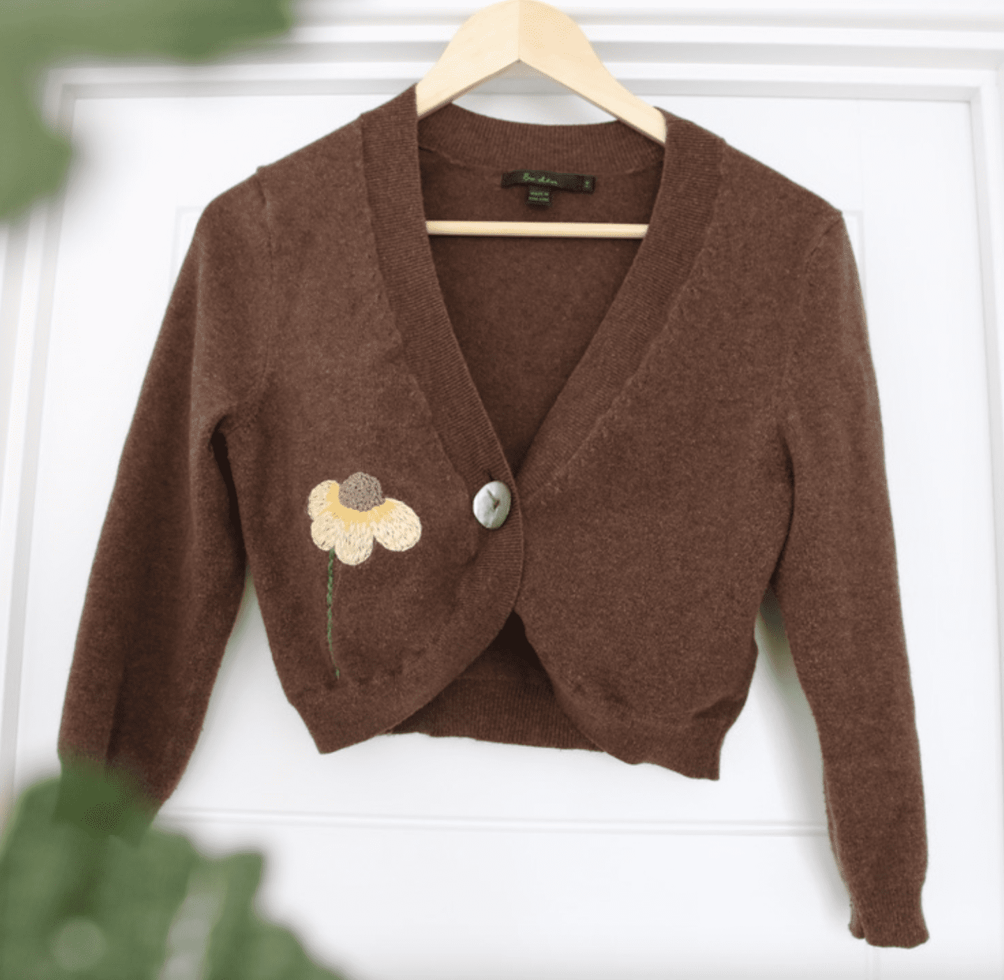 Small brown cropped cardigan hand embroidered with a large calendula flower on the side