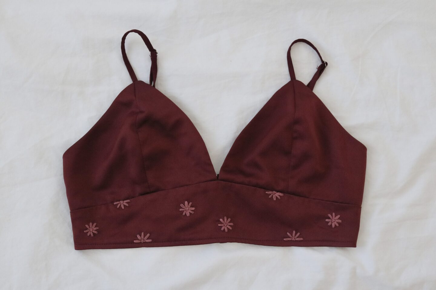 A deep red wine coloured bralette hand embroidered with dusty red hued flowers