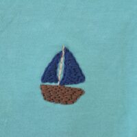 A hand embroidered navy blue sailboat on a turquoise tee