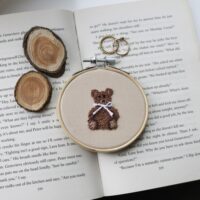 A 3 inch wall hanging decoration of a hand embroidered teddy bear