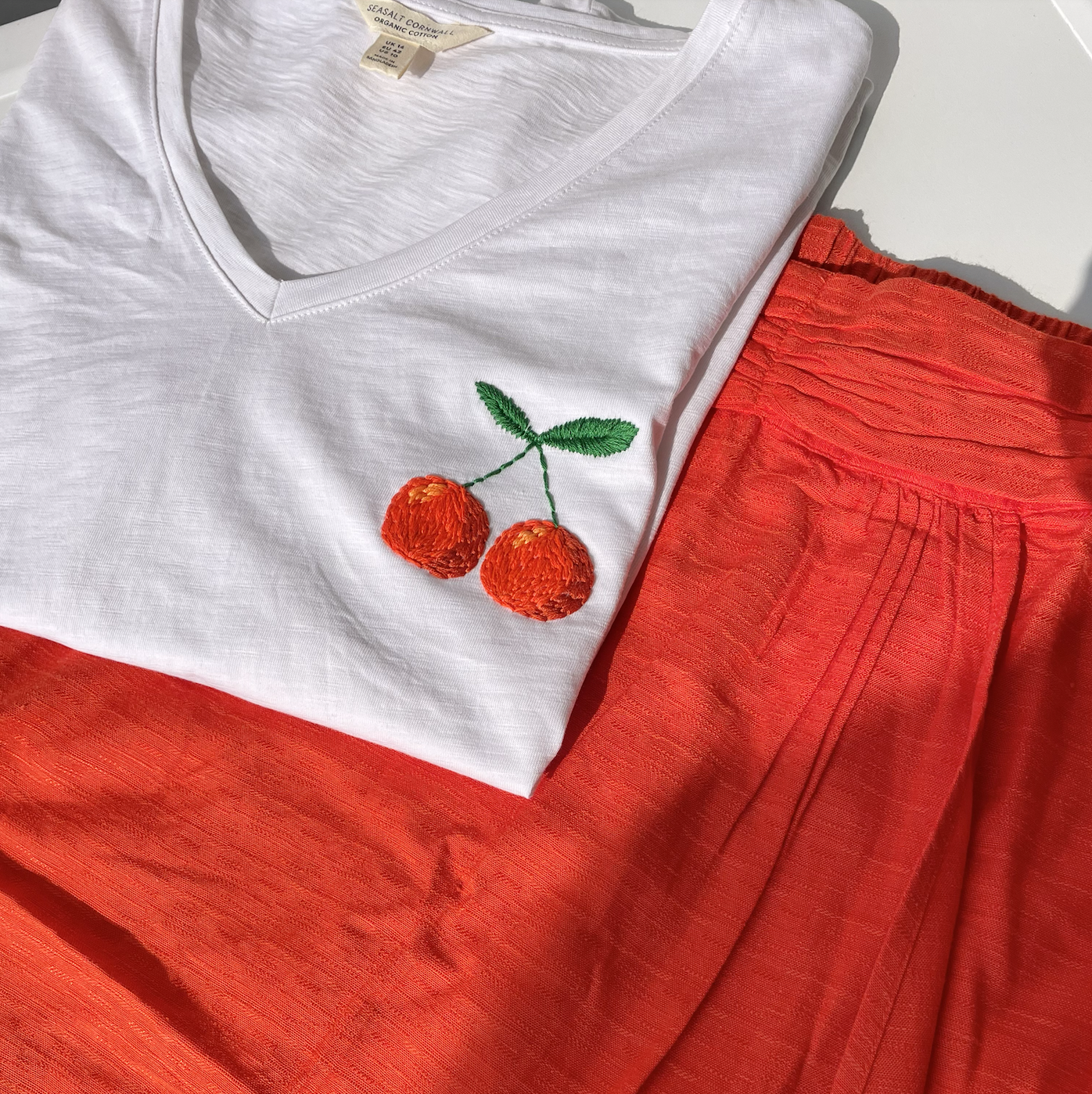 A white t-shirt with a hand embroidered pair of oranges to match an orange maxi skirt