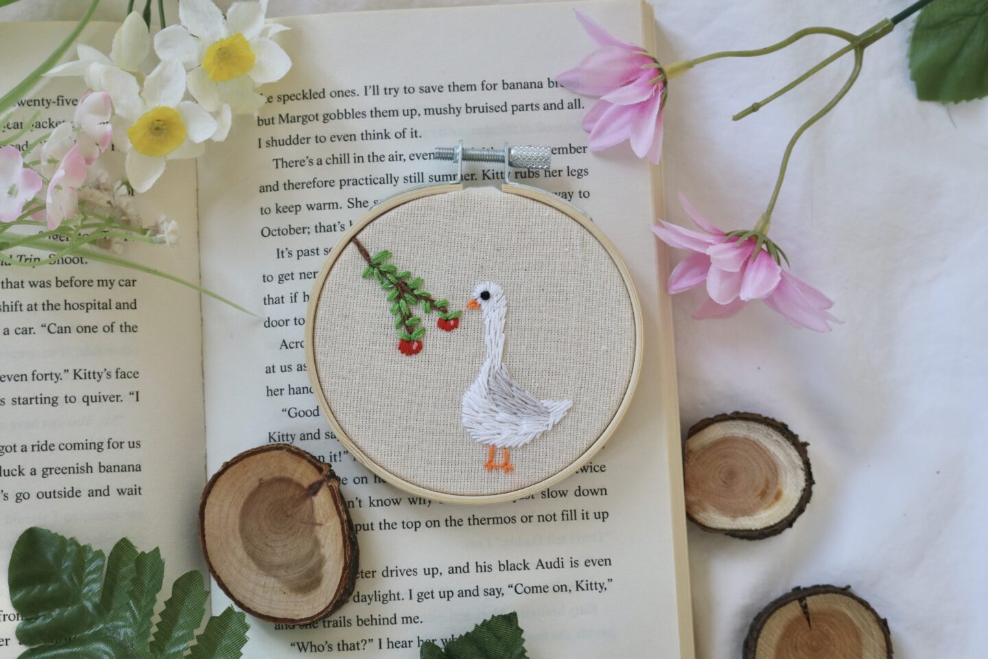 A 3 inch bamboo embroidery hoop hand embroidered with a white goose and apple tree branch