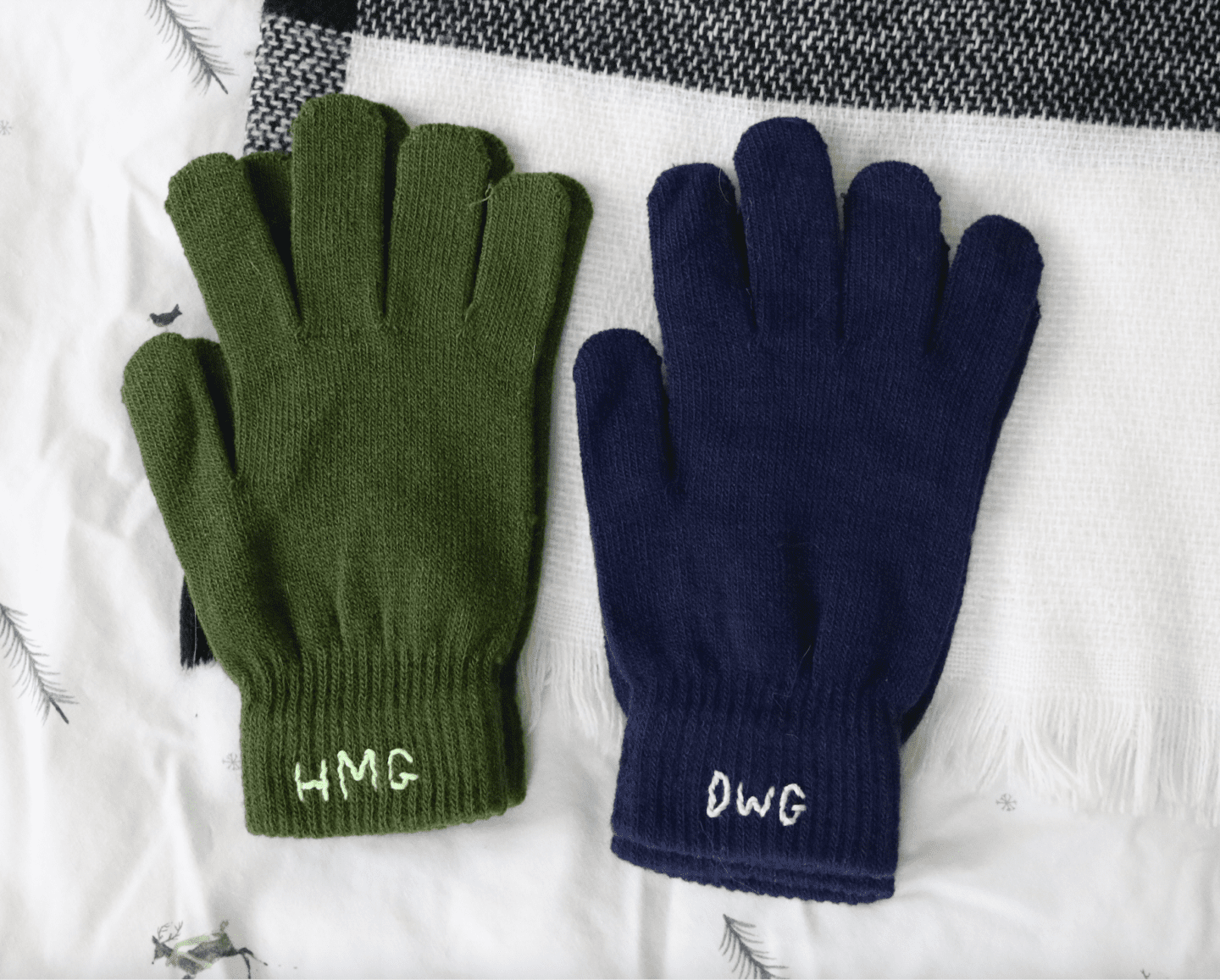 Two pairs of gloves, one green with 'HMG' initials embroidered in a light green and the other pair navy with 'DWG' embroidered in light blue on the cuff