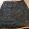 A denim skirt hand embroidered with sunflowers and bees