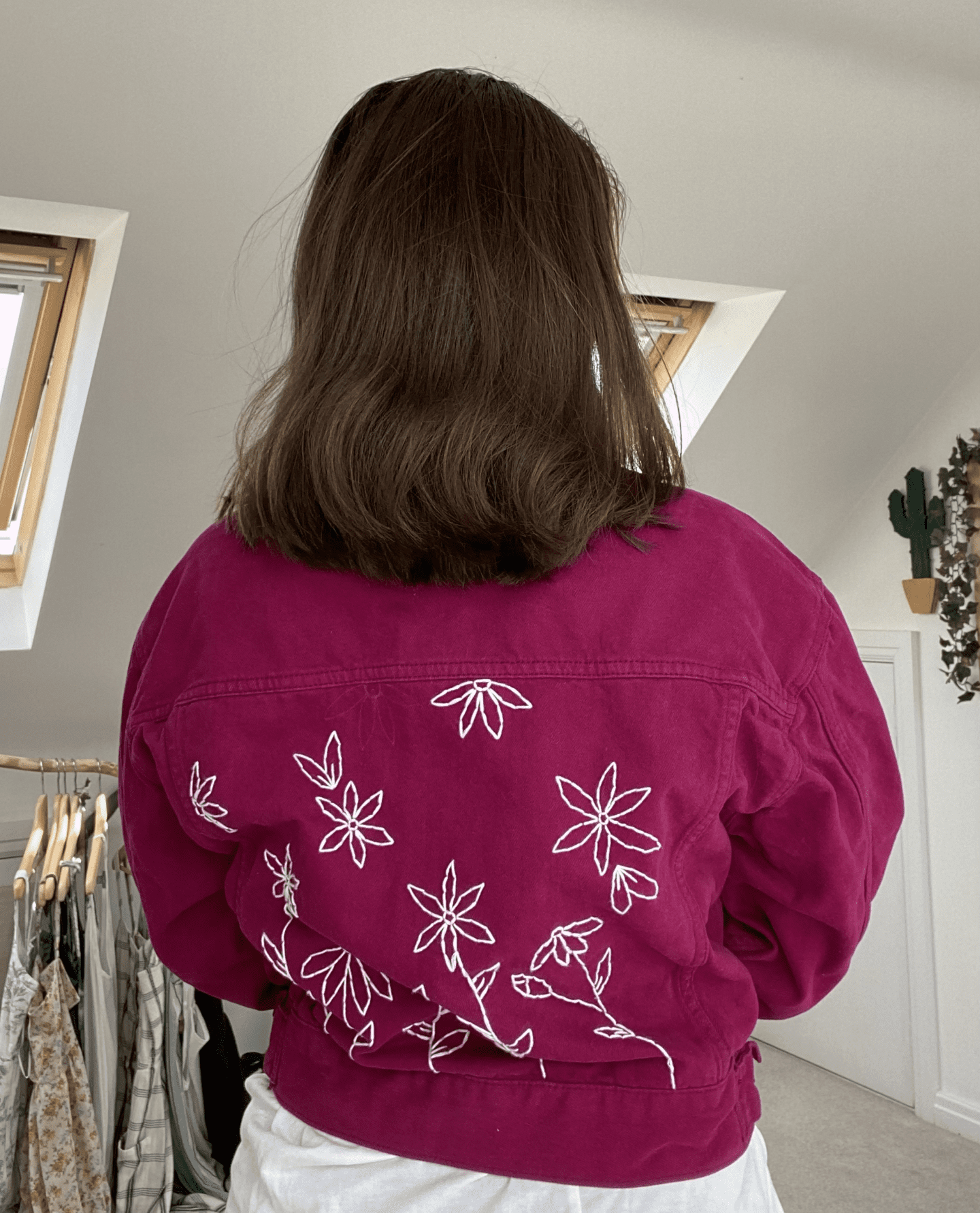 A brunette girl wearing a purple denim jacket hand embroidered with white flowers