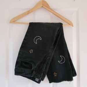 Black denim jeans hand embroidered with moons and stars
