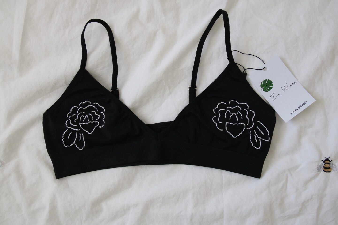 A black bralette hand embroidered with white rose outlines