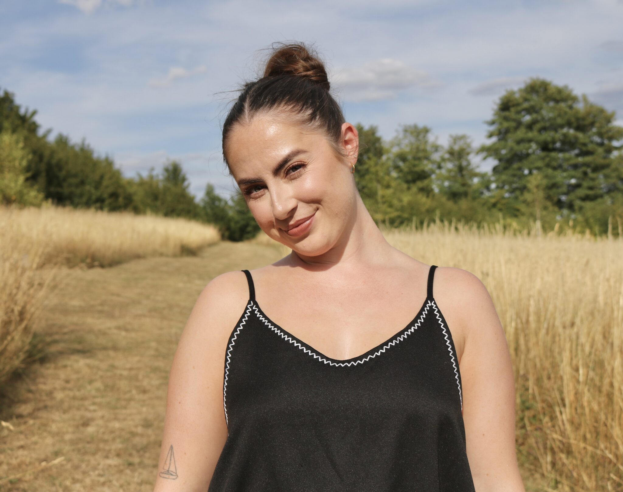 A brunette girl wearing a black dress hand embroidered with a white zigzag trim around the neckline