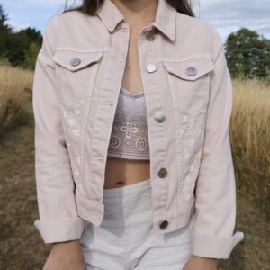 A pink denim jacket hand embroidered with daisies