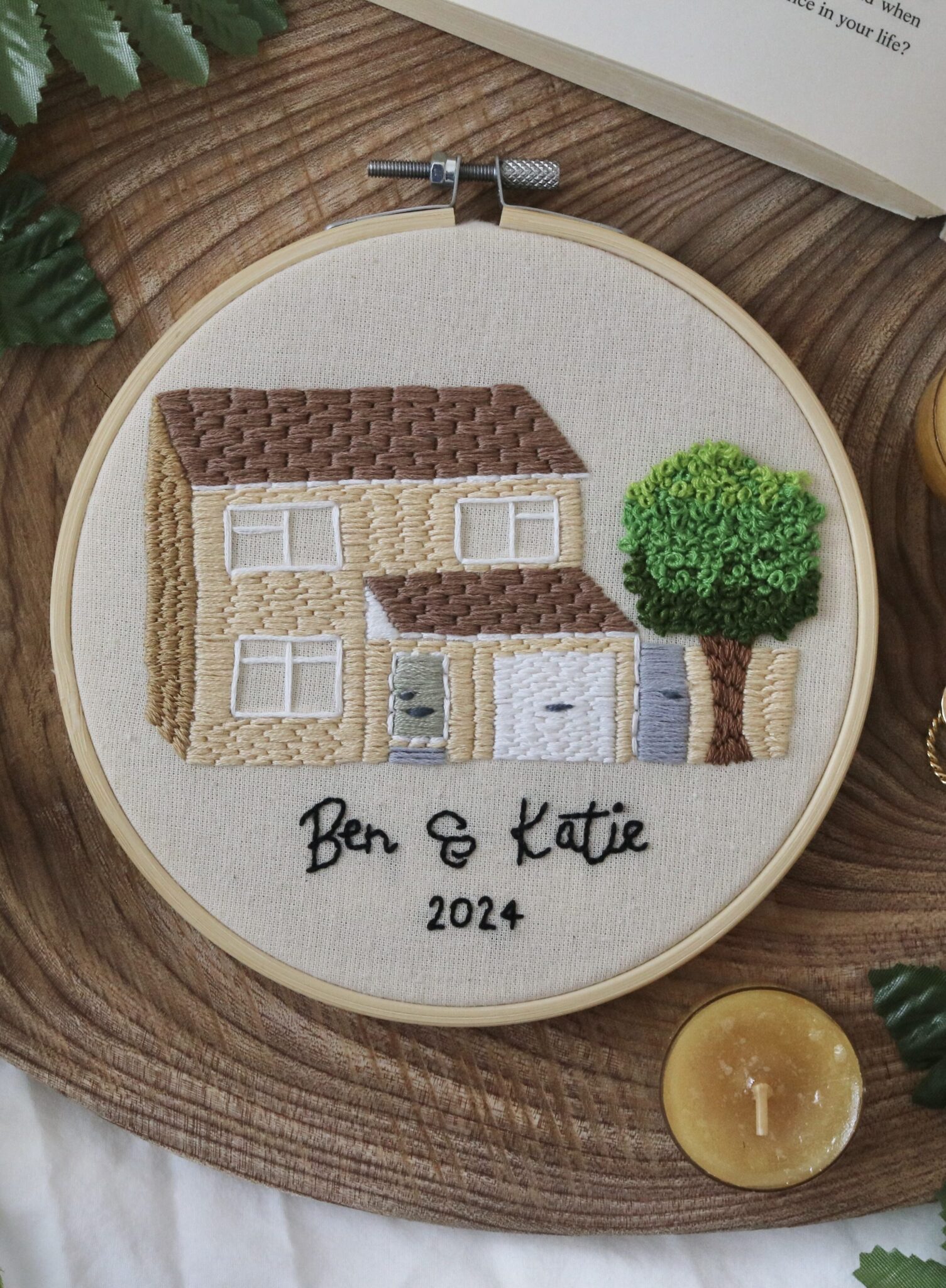 a 6 inch hoop hand embroidered with the front of a custom house with the names 'Ben & Katie' and the year '2024'